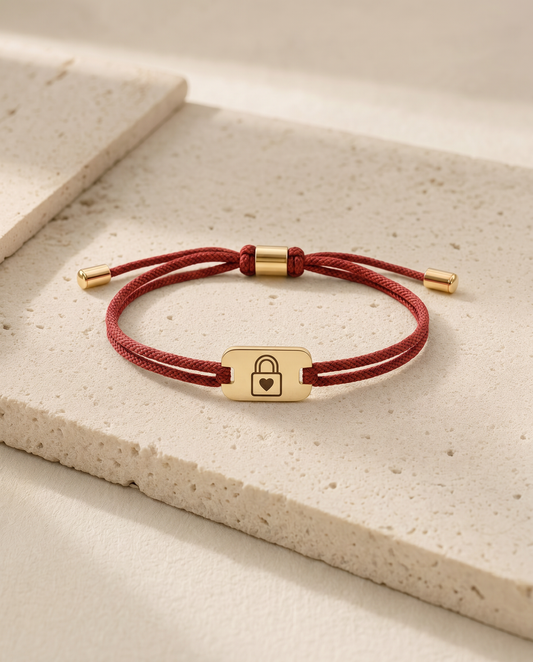The Taken status bracelet, red cord, gold tag